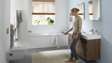 Une femme range des produits dans l’armoire de toilette