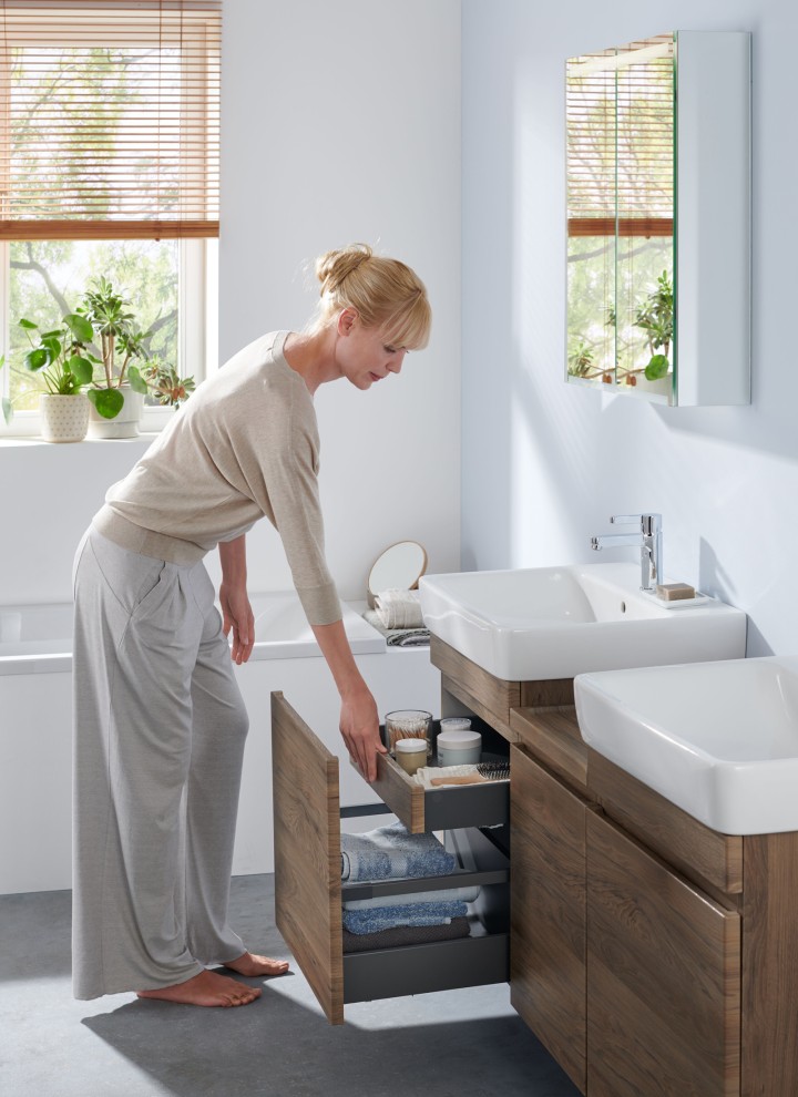 Femme dans une salle de bains blanche de la ligne Geberit Renova Plan Femme dans une salle de bains blanche de la ligne Geberit Renova Plan