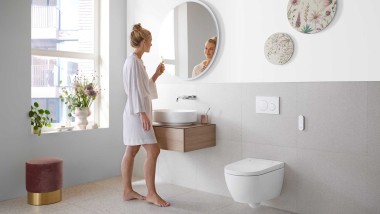 Femme dans une salle de bains blanche avec meubles et céramiques