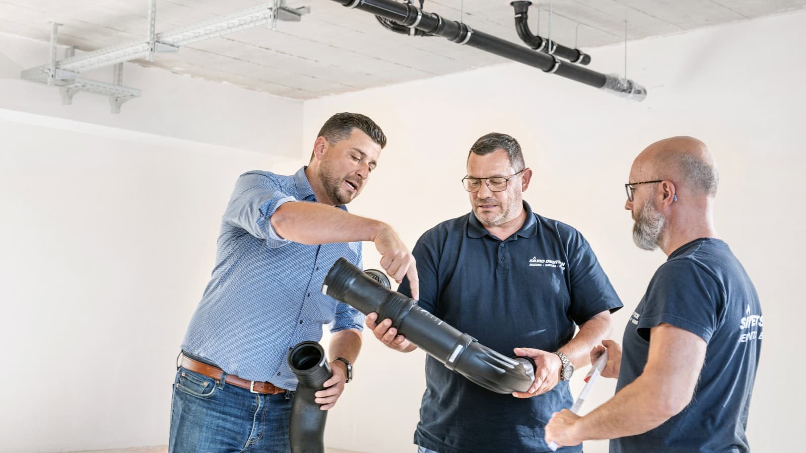 Fabian Ritter, responsable commercial chez Geberit, présente le nouveau coude BottomTurn Silent-Pro au chef de projet Marcel Roth et à son équipe Fabian Ritter, responsable commercial chez Geberit, présente le nouveau coude BottomTurn Silent-Pro au chef de projet Marcel Roth et à son équipe